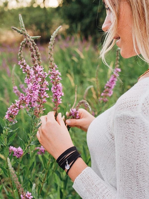 a black wrap bracelet on arm holding flowers