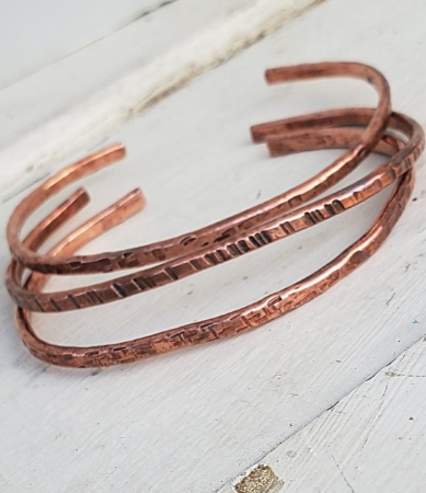Hand forged copper cuff stack on white distressed wood