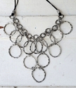 Textured silver circle bib necklace on white trunk