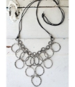 full view silver circle bib necklace on white distressed wood
