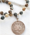 Detailed old coin earthy gemstone necklace on white distressed wood