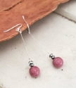 Long silver pink gemstone earrings on wood