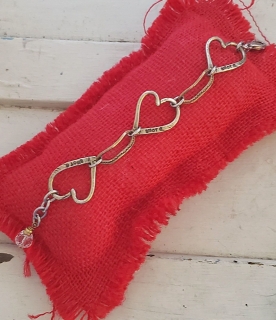 bronze triple heart bracelet on red pillow