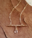 bronze bar necklace with stone in center on wood