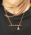 model wearing bronze bar necklace with offset clear stone