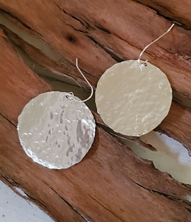 big handcrafted silver disc earrings on wood