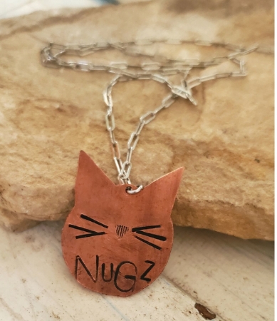 Copper cat face necklace on rock