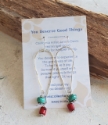 carded silver elongated loop earrings with red and teal gemstones