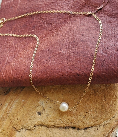 white pearl gold chain necklace on leather & rock