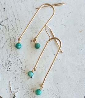 gold arc green gemstone earrings on distressed white