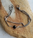 Silver box chain, double strand black gemstone displayed on rock