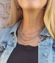 feminine silver layered necklace with silver oval earrings on model