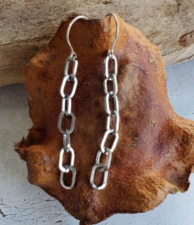 long silver chain link earrings on wood display