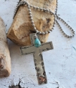 long silver cross turquoise bead necklace on rock