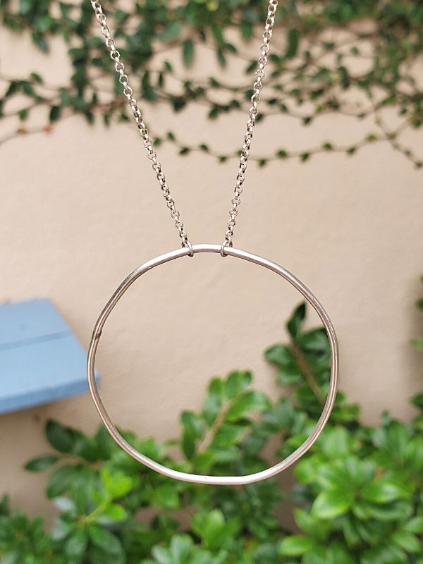 silver circle necklace hanging in the garden