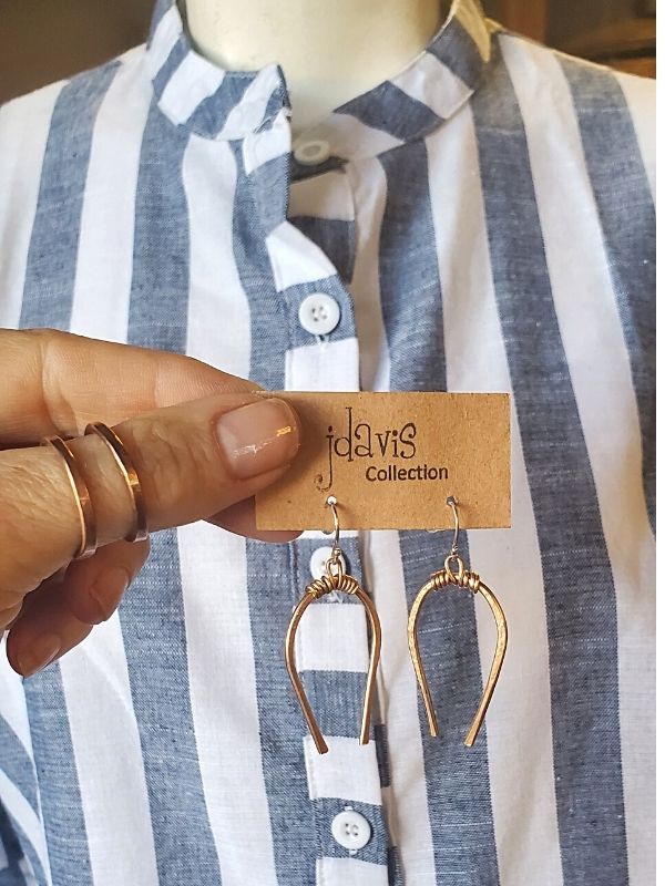 holding horseshoe earrings with thumb rings against a striped outfit