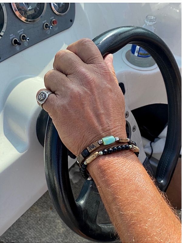 guy with bracelets on arm while driving a boat