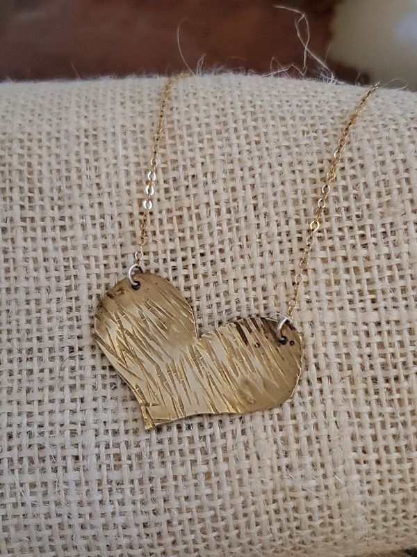 gold textured heart necklace on cream burlap