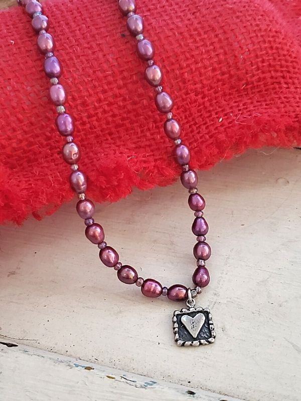 purple pearl heart necklace with red pillow